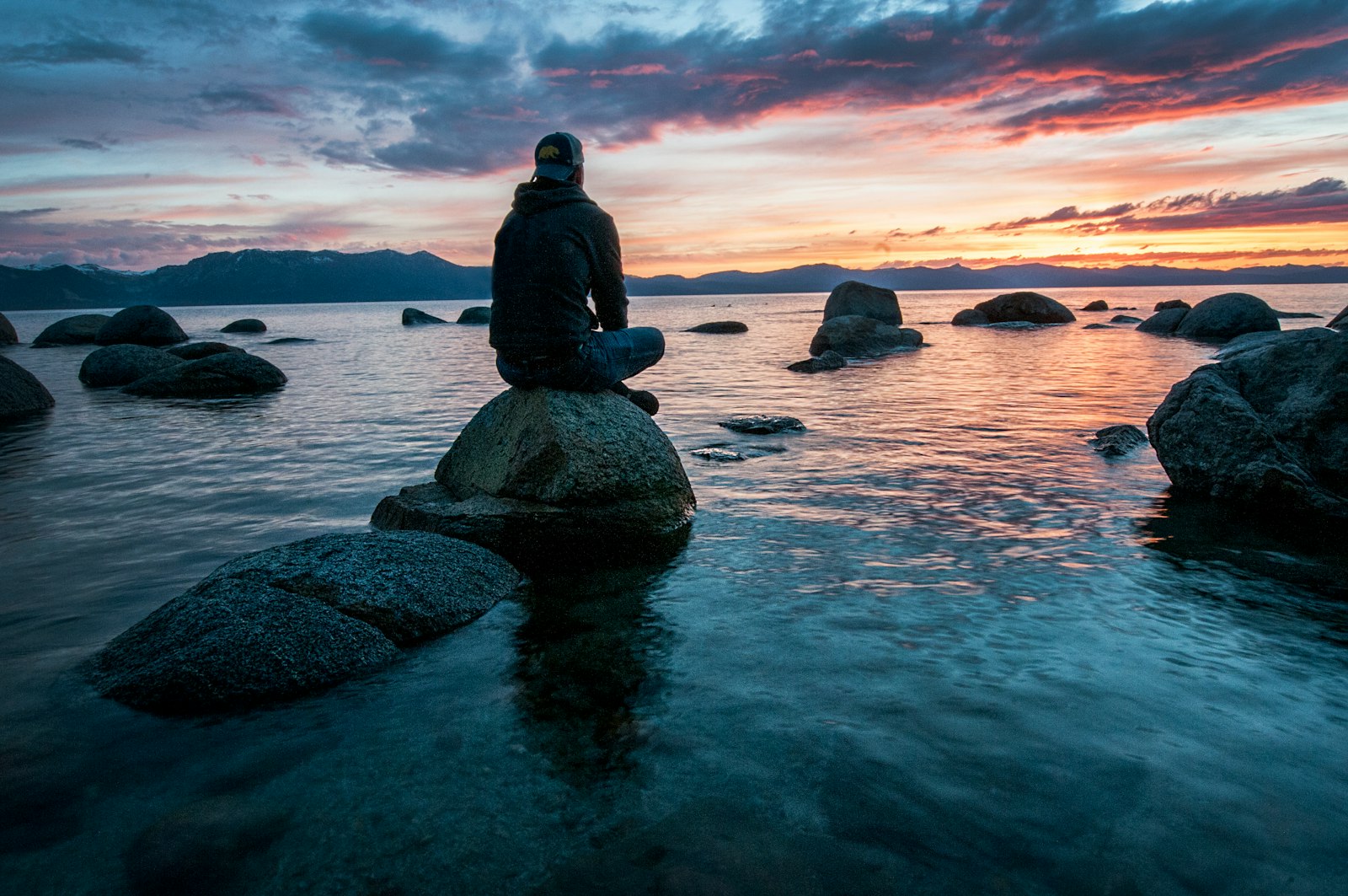 A solitary person beside a wide lake during a peaceful moment of healing