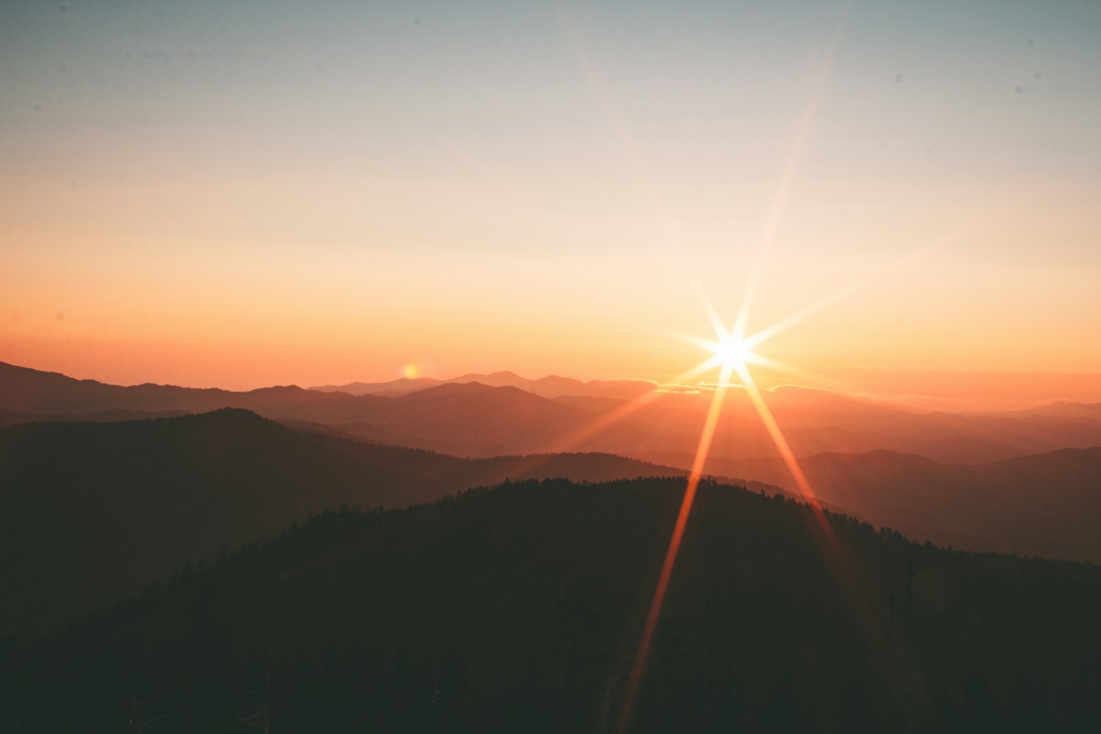 A quiet mountain landscape beneath a soft sunrise